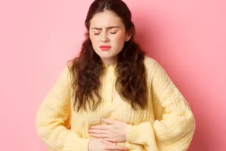 Junge Frau hält sich den schmerzenden Bauch